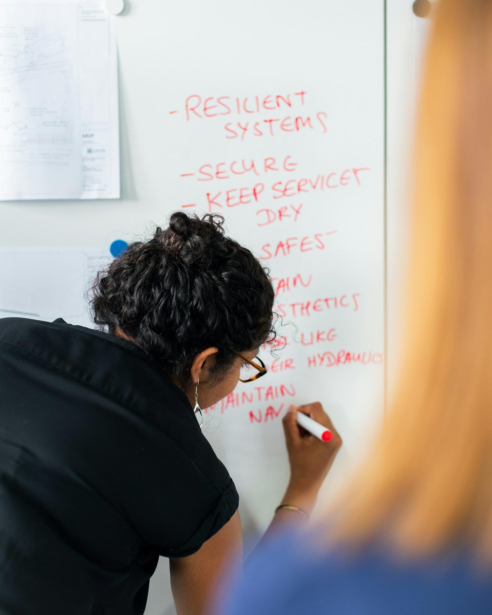 En kollega skriver upp prioriteringar på en whiteboard under ett planeringsmöte