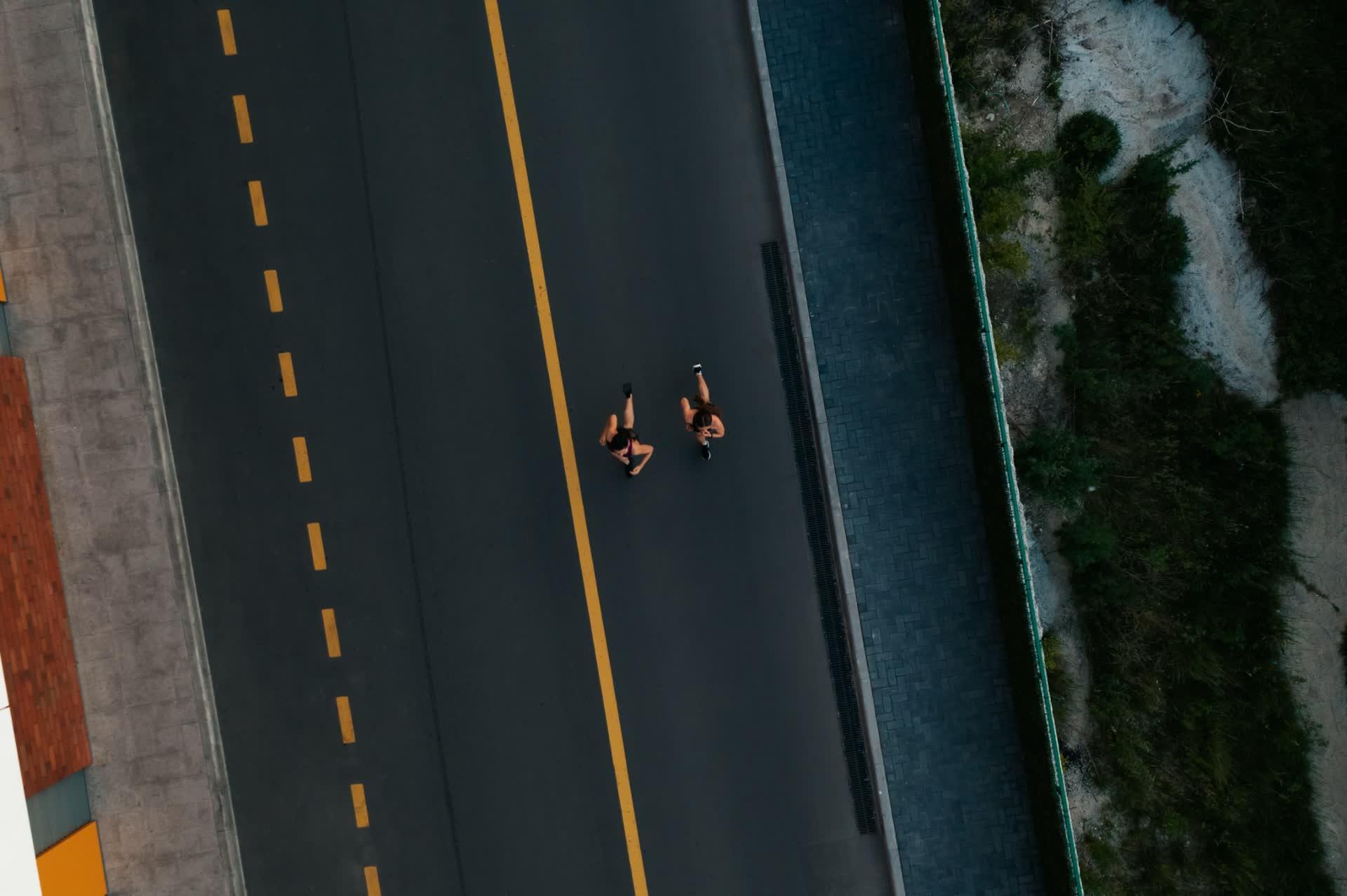 Two people running side by side on a road, seen from above