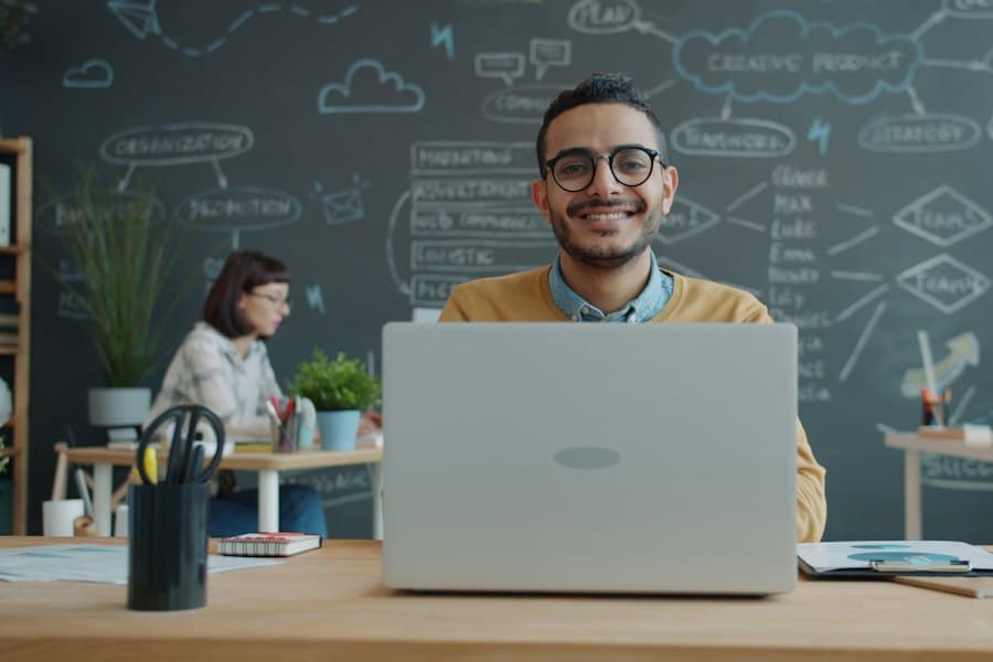 Un uomo sorridente che lavora al portatile in ufficio