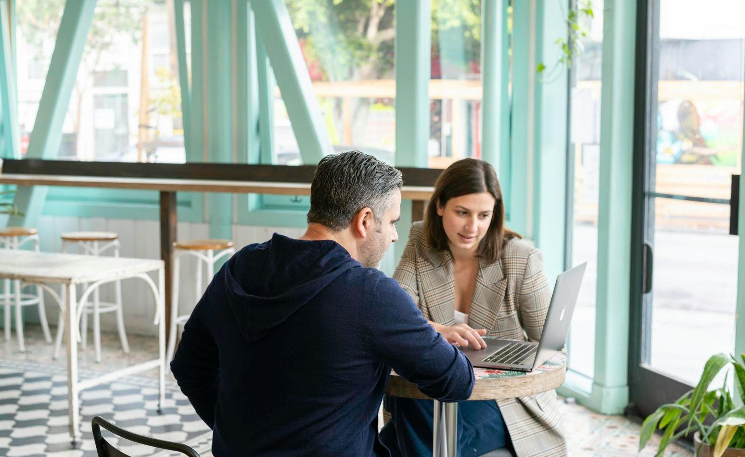 Um consultor analisa as finanças com uma cliente em frente ao portátil