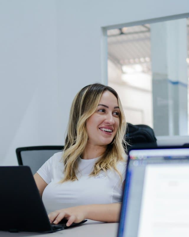 Una collaboratrice sorridente lavora al portatile in ufficio