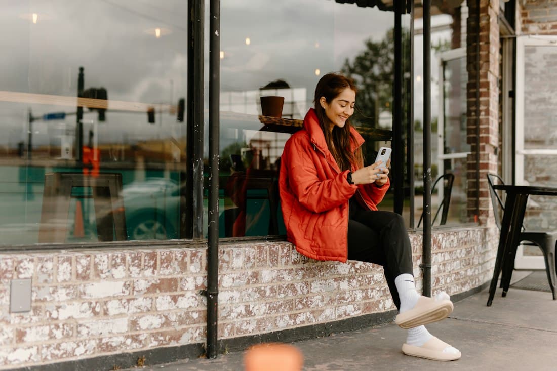 Een vrouw die op haar telefoon leest voor een café