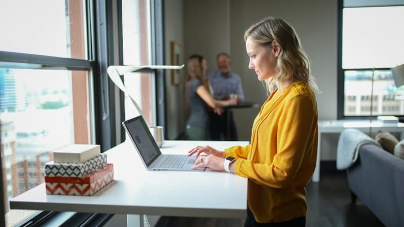 Een vrouw werkt aan een sta-bureau in een licht kantoor