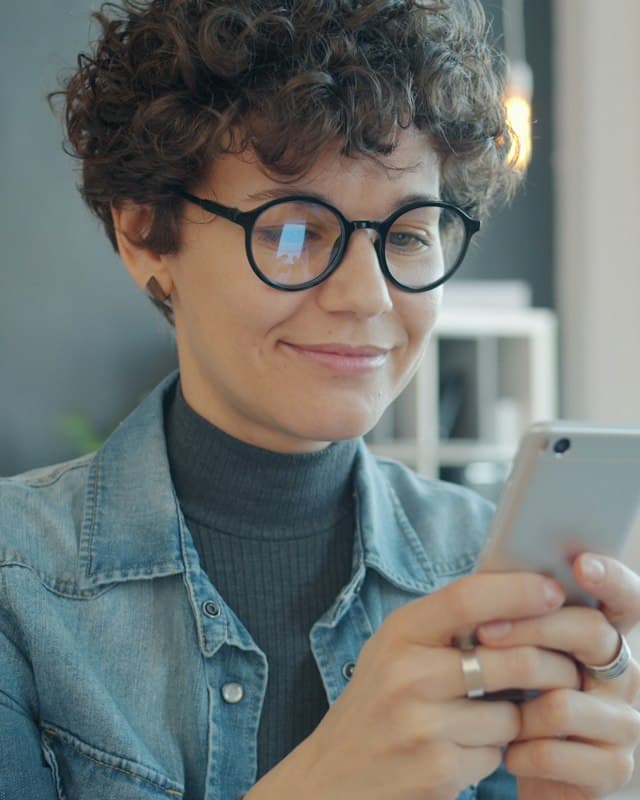 Donna sorridente che legge sul telefono