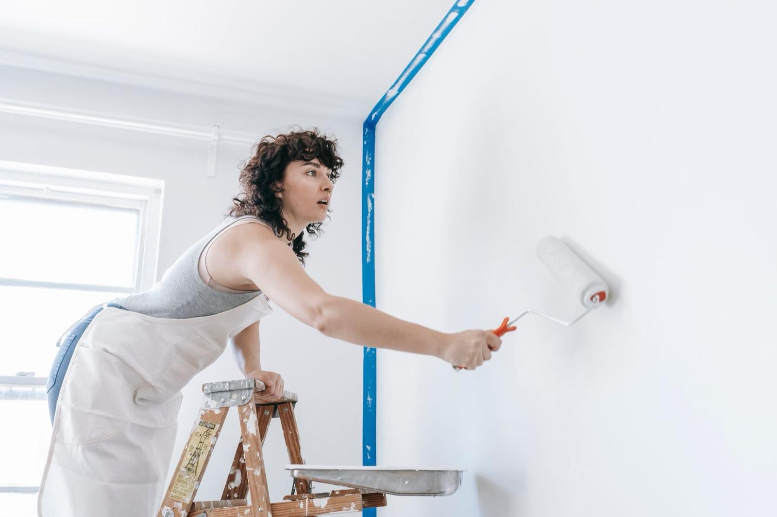 A painter rolling a white wall