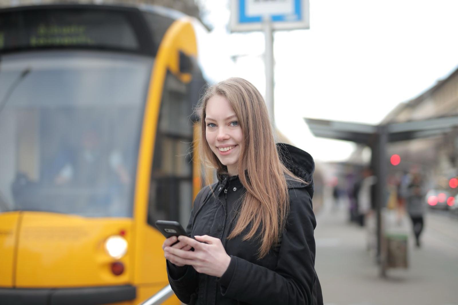 A woman by a tram reading on her phone