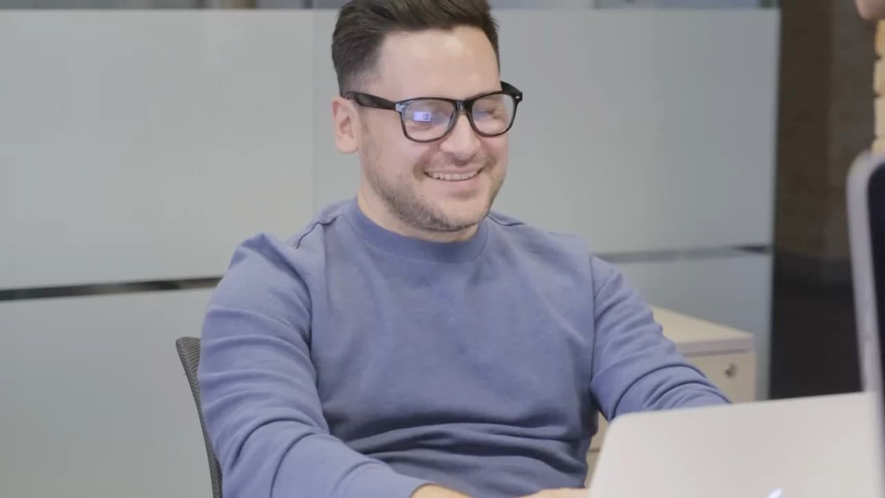 A smiling man working at his laptop in the office